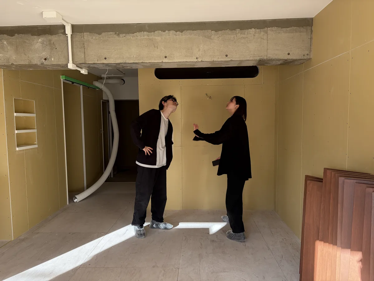 壁の上部にある角の丸い横長の開口と、その下に立つご夫婦